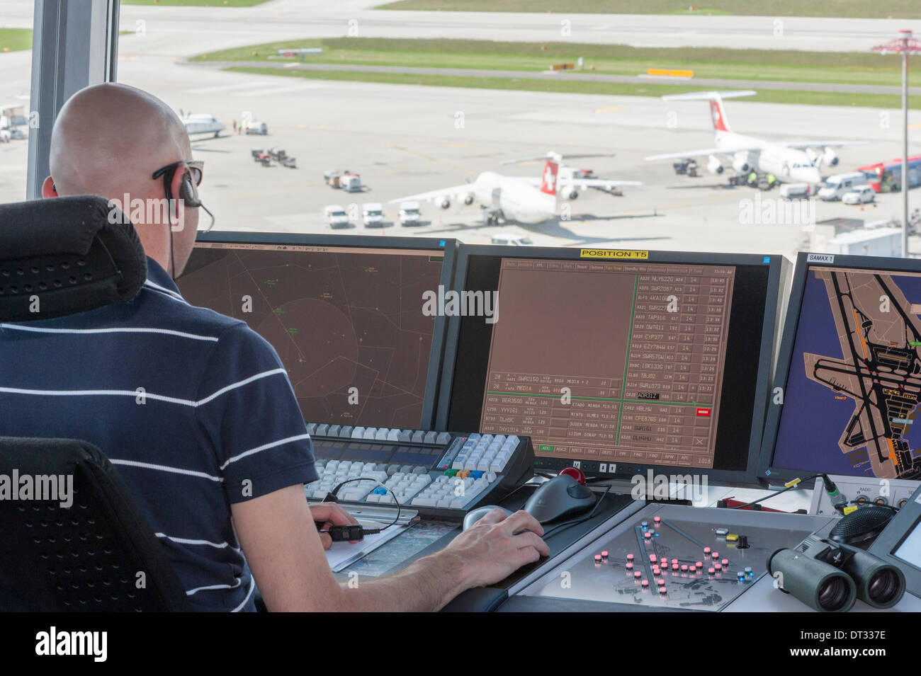 An air traffic controller in the control tower of Zurich/Kloten international airport is monitoring the airport's airfield. Stock Photo