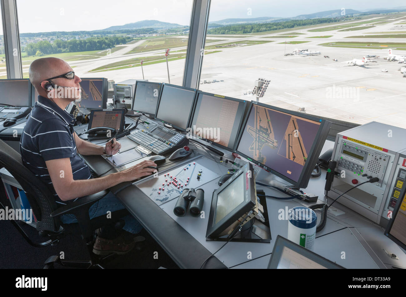 An air traffic controller in the control tower of Zurich/Kloten international airport is monitoring the airport's airfield. Stock Photo