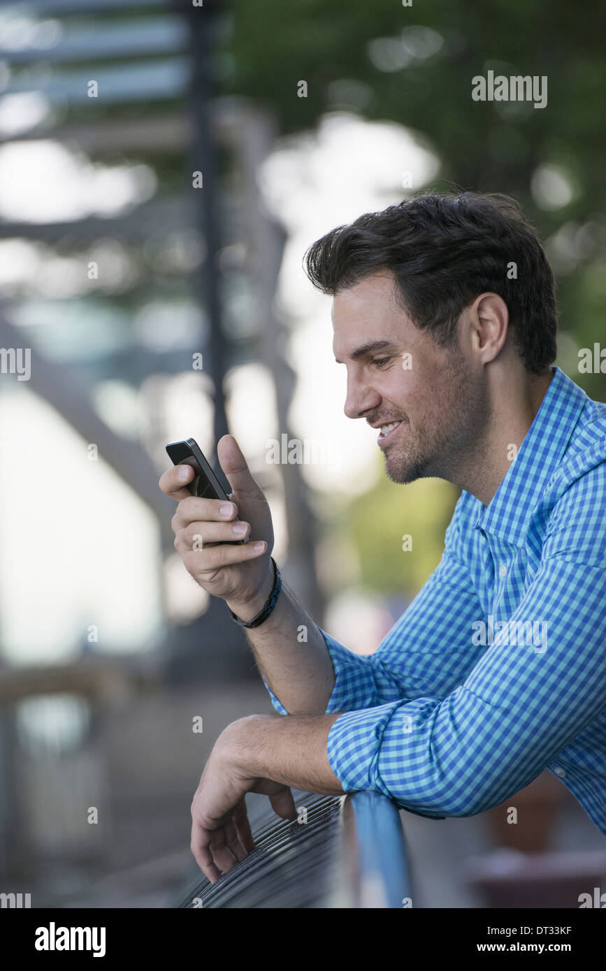 A man in a blue shirt using a smart phone Stock Photo