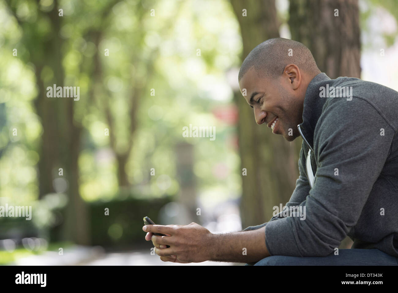 A man in a grey zipped sweatshirt using his smart phone Stock Photo