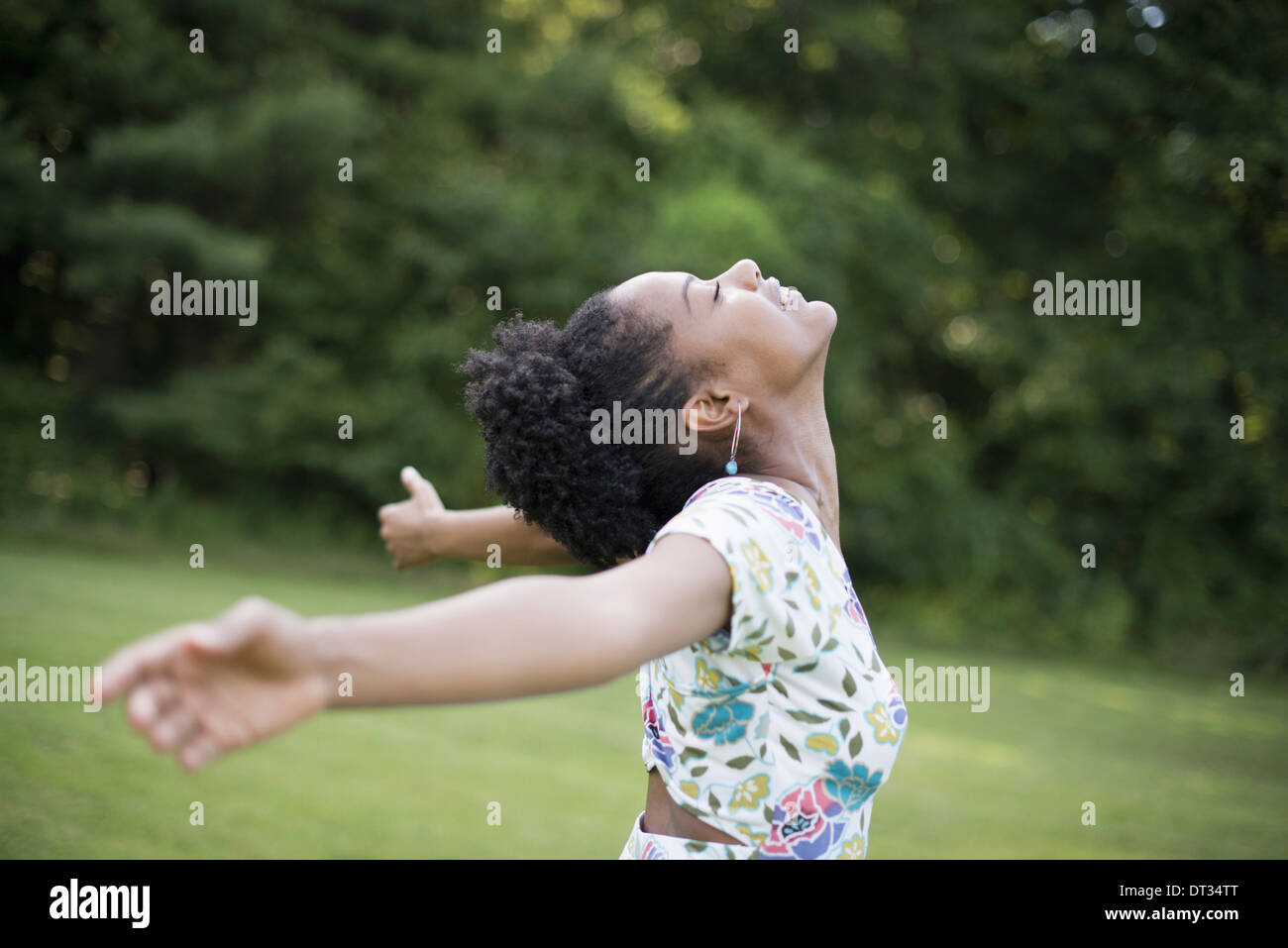 A young woman in a summer dress with her arms outstretched celebrating freedom Stock Photo