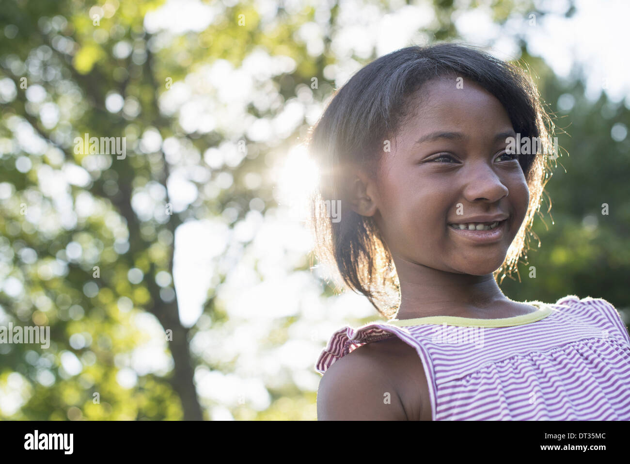 A young girl with short hair in a striped sundress smiling Stock Photo