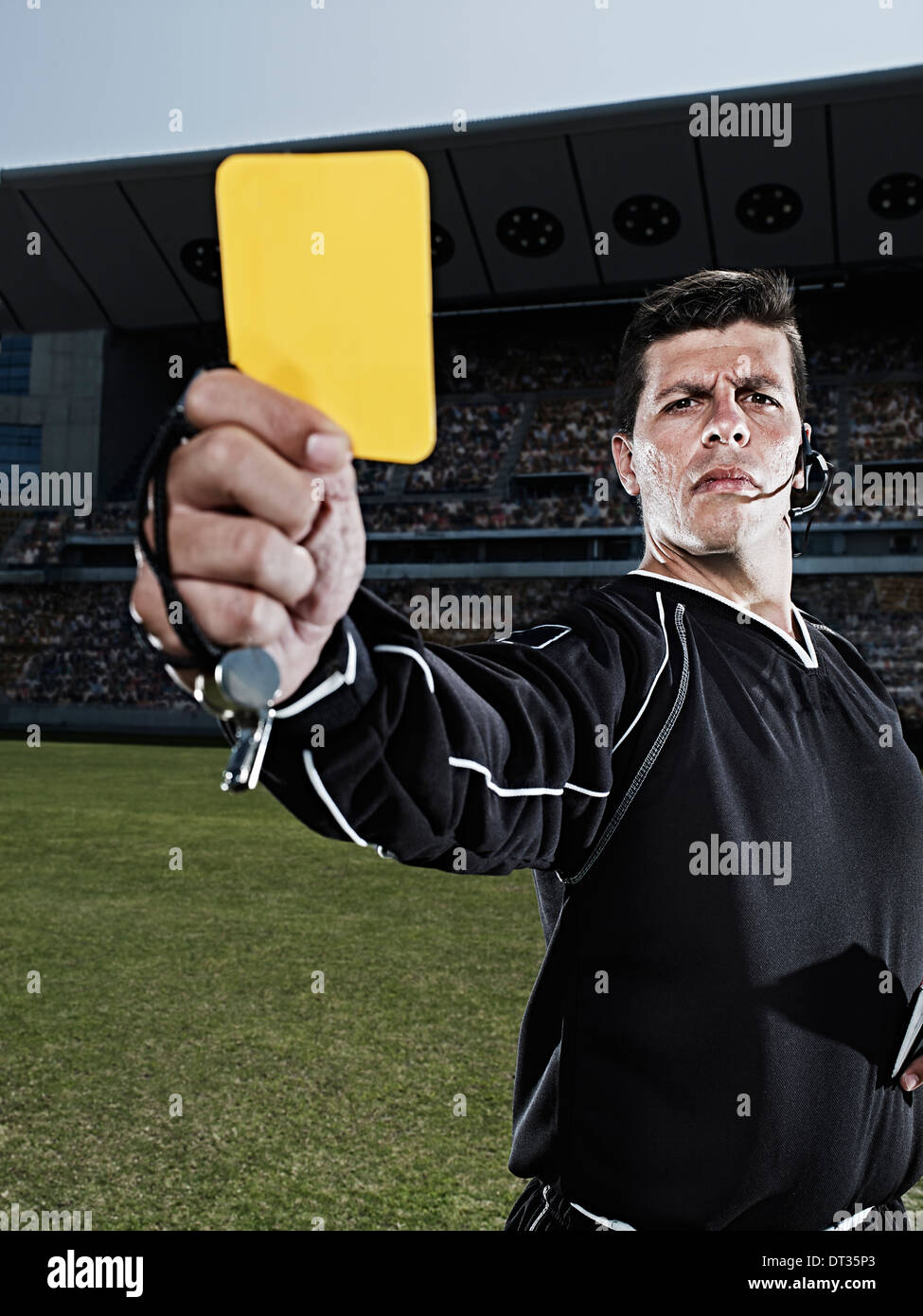 Referee flashing yellow card on soccer field Stock Photo