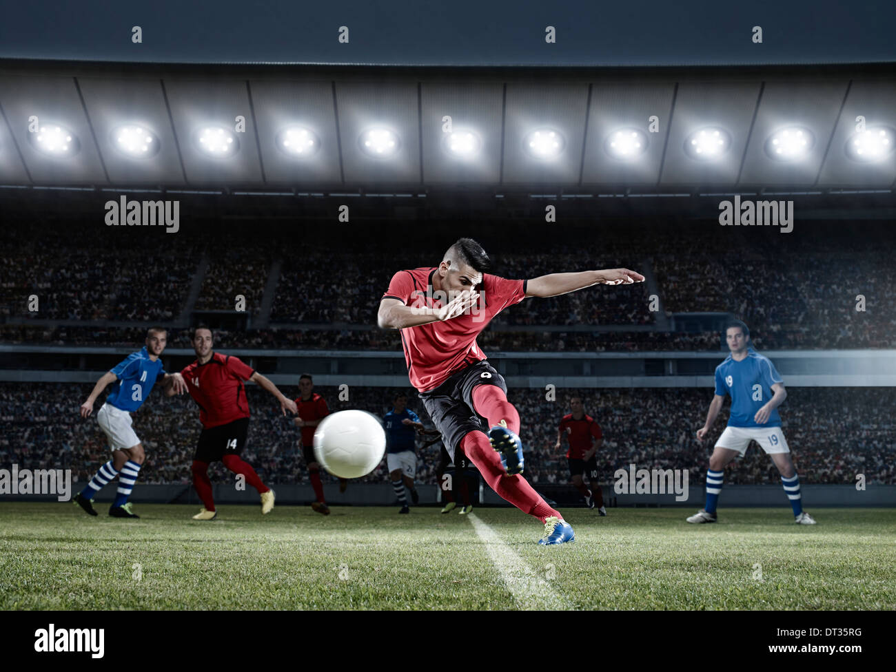 Soccer player kicking ball on field Stock Photo
