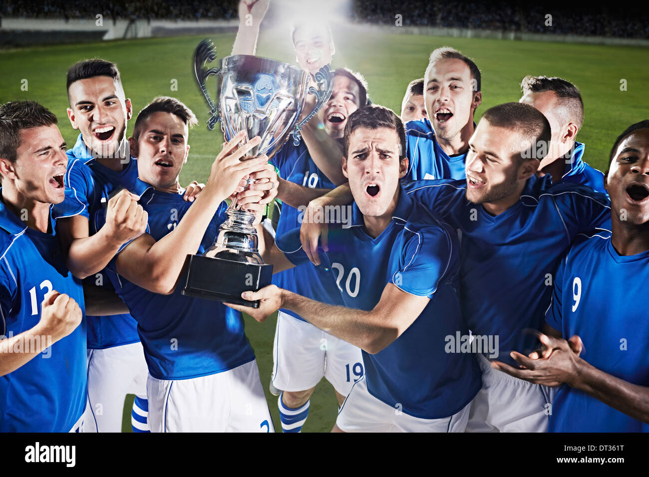 Soccer team cheering with trophy on field Stock Photo