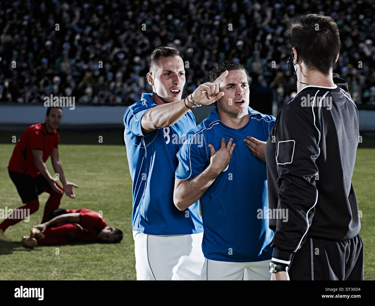 Soccer players arguing with referee on field Stock Photo