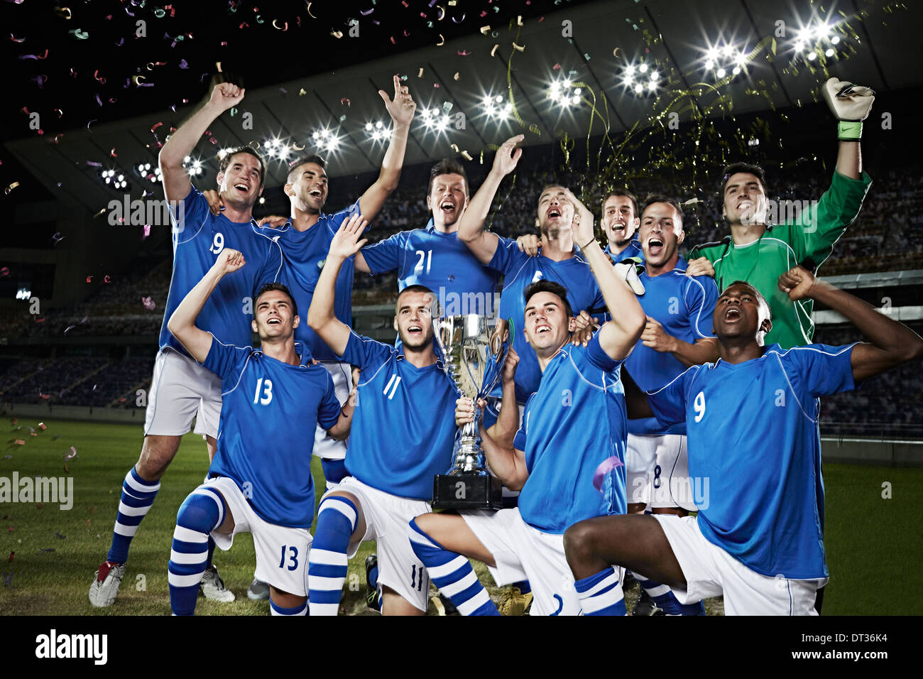 Soccer team cheering with trophy on field Stock Photo