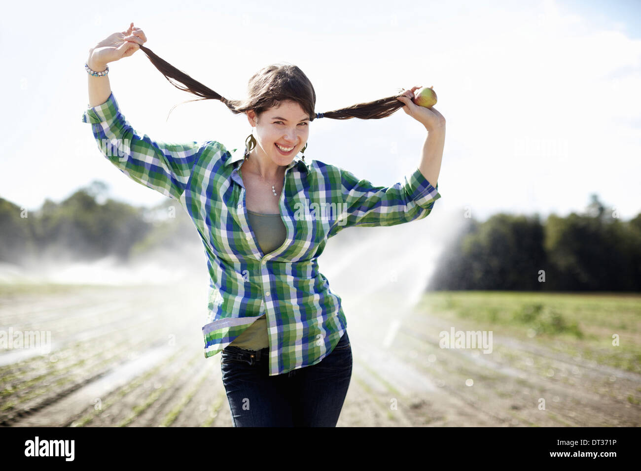 A girl standing in a field irrigation sprinklers working Stock Photo