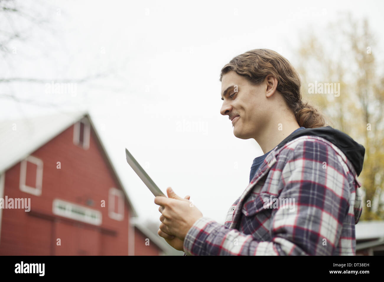 A young man using a computer tablet, a portable PC tablet device, on an organic farm. Stock Photo