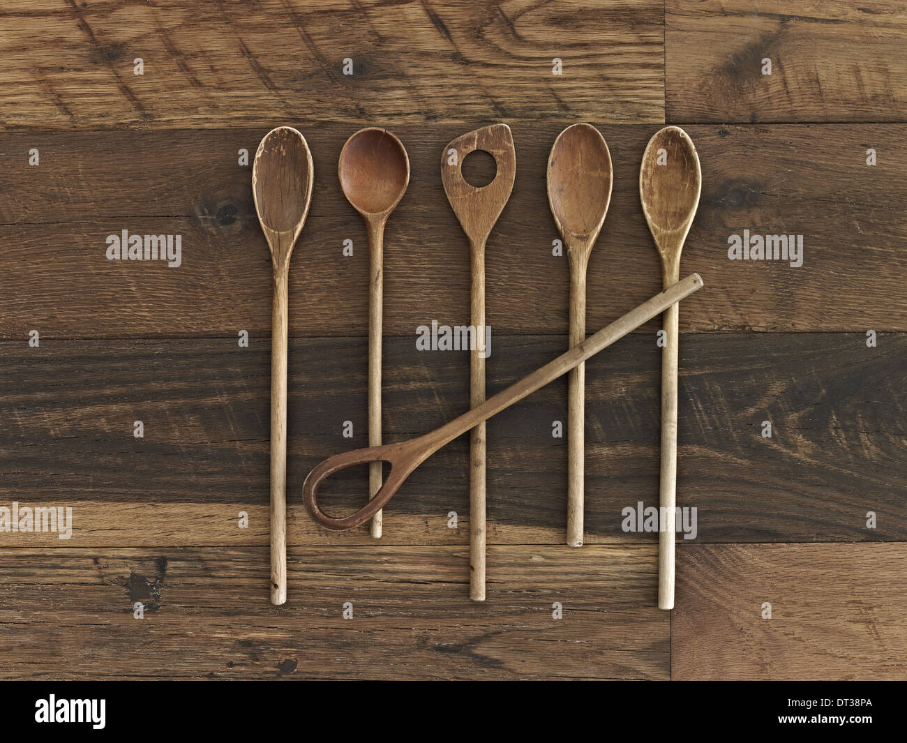 An arrangement of six wooden spoons of a variety of shapes and sizes on a wooden table. Stock Photo