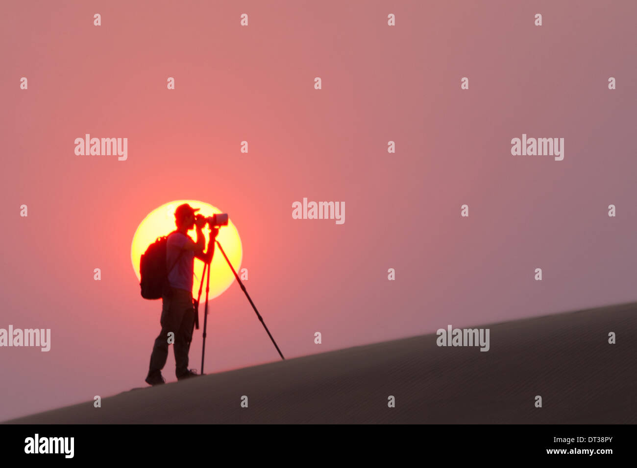 Photographer silhouetted in the setting sun in the Namib Desert, Namibia Stock Photo