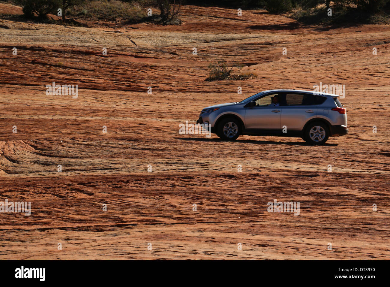 car driving on stripped layered rock, southern Utah Stock Photo