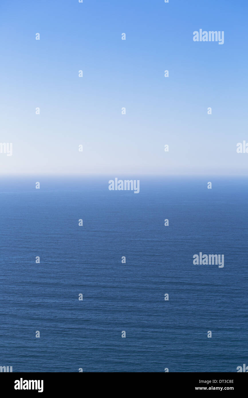 A view over the Pacific Ocean and a calm sea, merging into the blue sky. Stock Photo