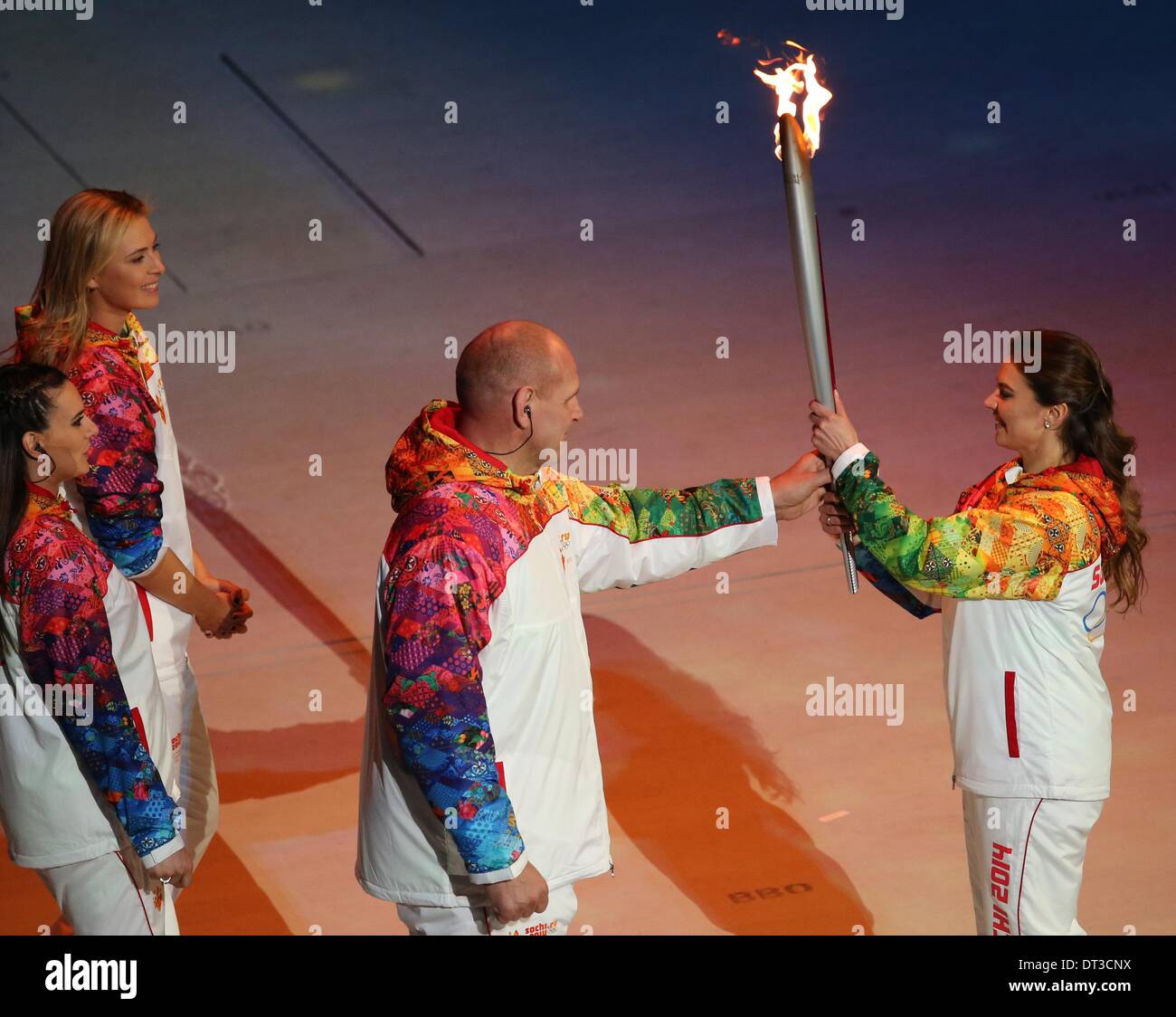Sochi, Russia. 07 February 2014. Alexandr Karelin (C) receives the Olympic torch from Alina Kabaeva (R) of Russia as Russian pole vaulter Yelena Isinbayeva and tennis player Maria Sharapova (back) of Russia follow during the Opening Ceremony in Fisht Olympic Stadium at the Sochi 2014 Olympic Games, Sochi, Russia, 07 February 2014. Photo: Fredrik von Erichsen/dpa/Alamy Live News Stock Photo