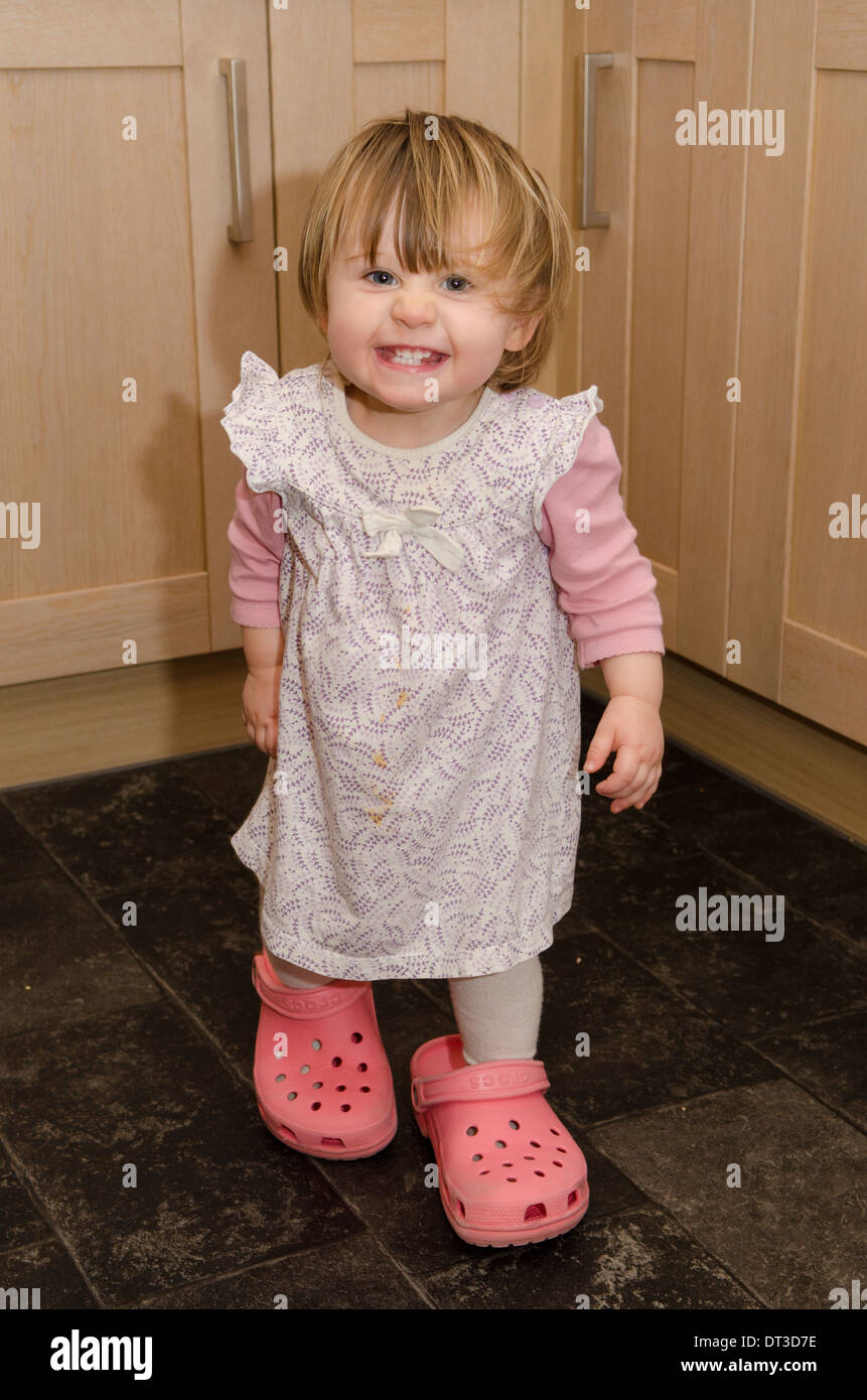 18 month old girl wearing mother's crocks shoes. Stock Photo