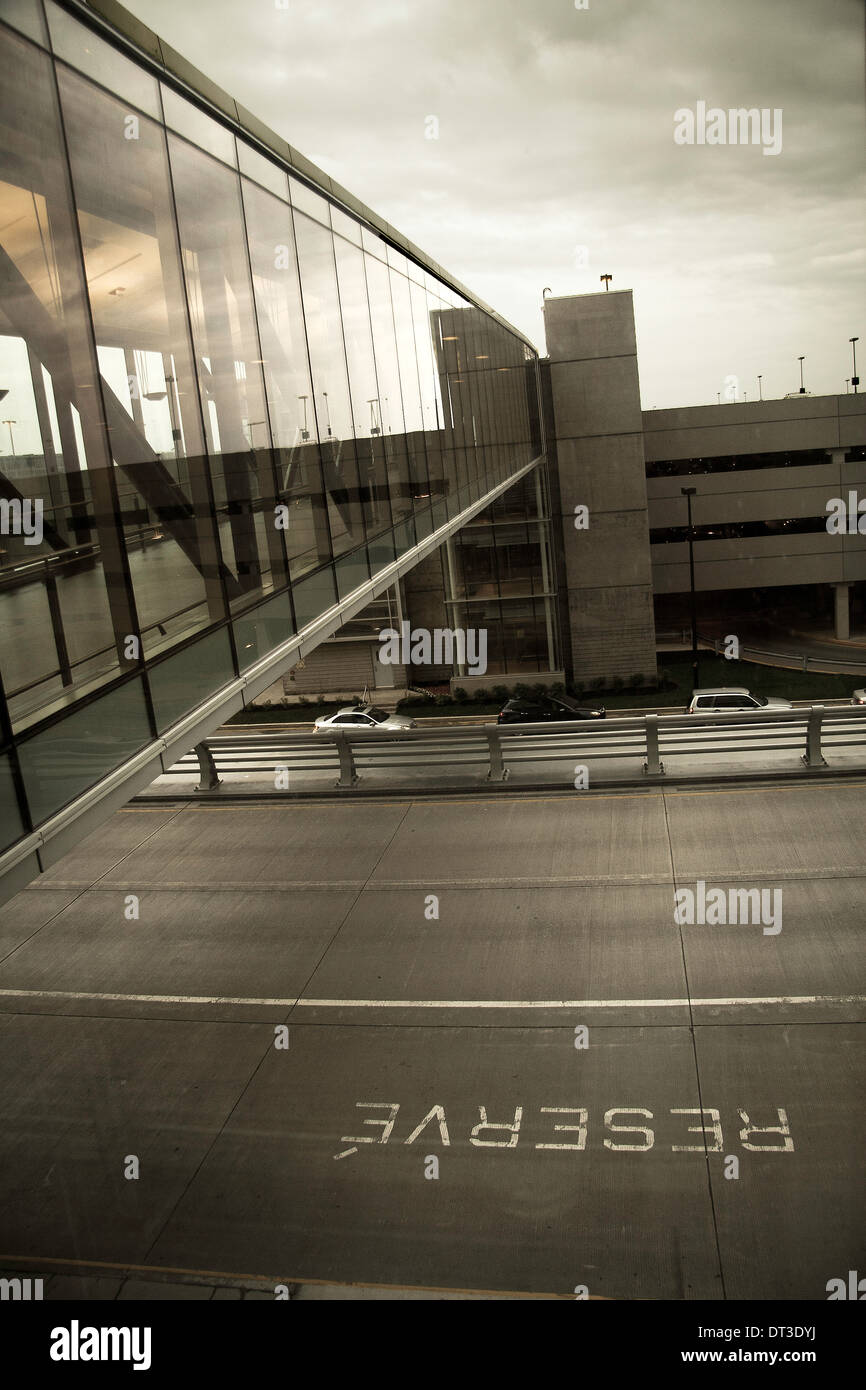A reflective sideways view of an airport walkway and parking lot. The road below has an upside 'Reserve' sign on it. Stock Photo