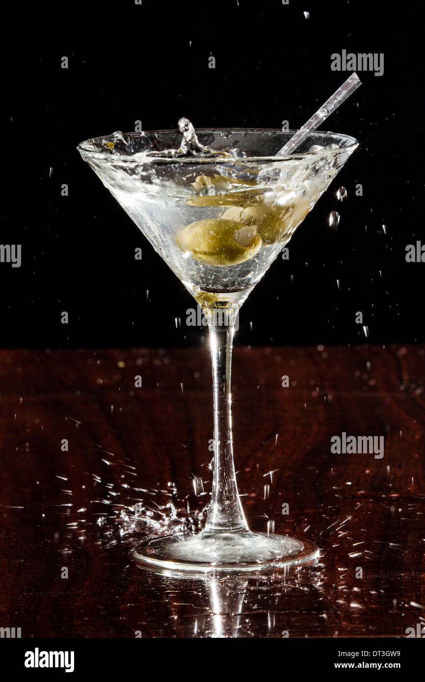 close up of garlic stuffed martini olives splashing into a cocktail