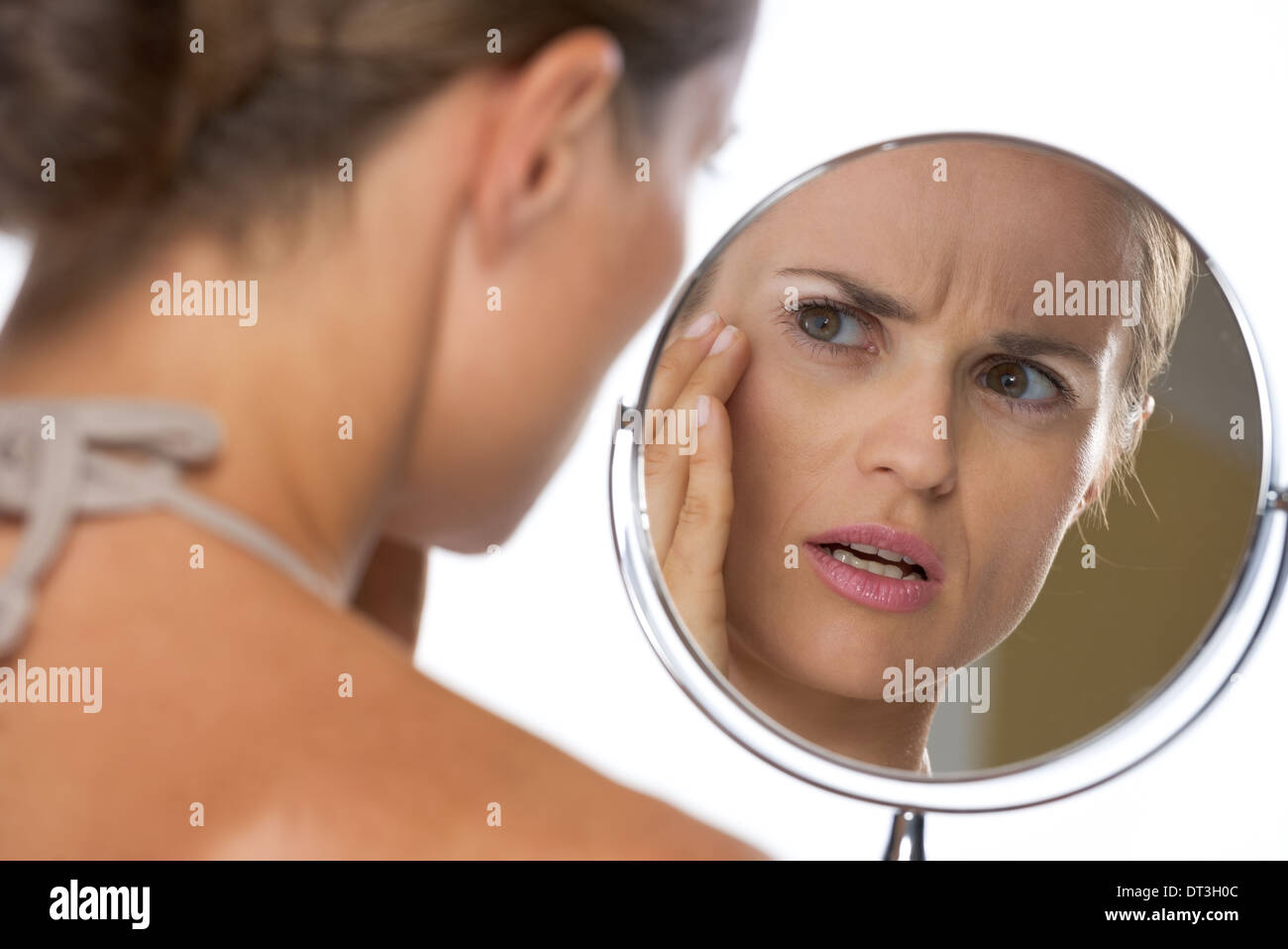 Concerned young woman looking in mirror Stock Photo