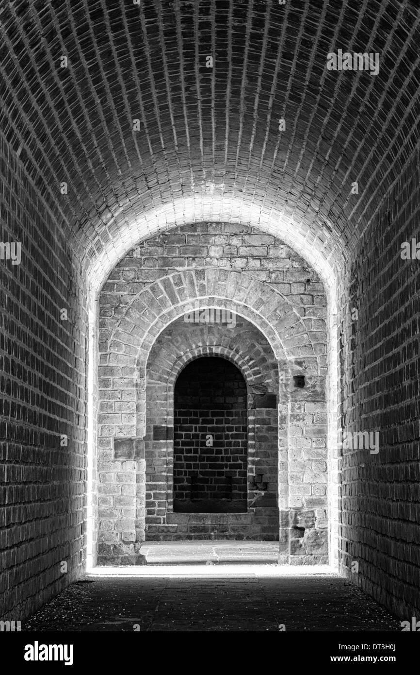 Brick-lined tunnel leading to an entrance in a Civil War Era fort. Converted to black and white. Stock Photo