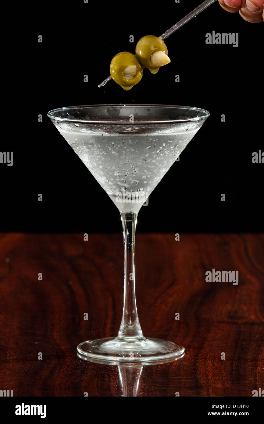 Garlic stuffed martini olives garnishing a sparking vodka martini Stock