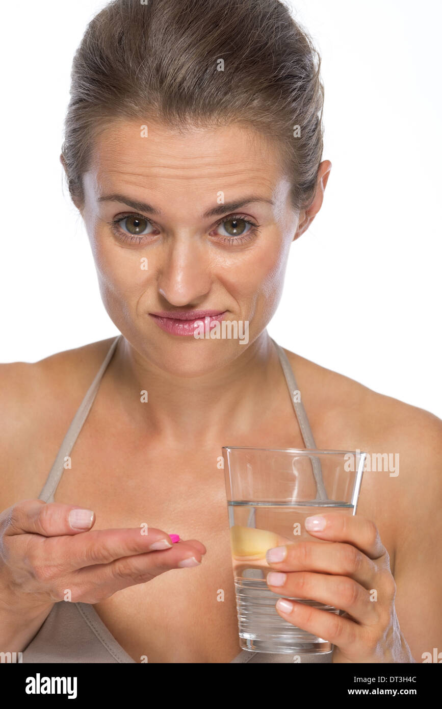 Doubting young woman with pill and glass of water Stock Photo
