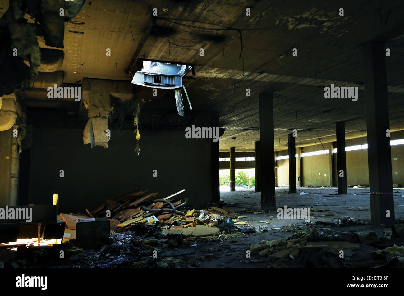 Abandoned factory interior tattered insulation material hanging from the ceiling. Stock Photo