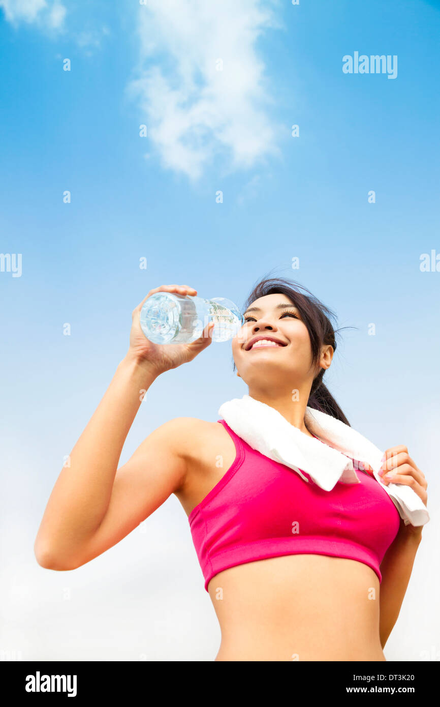 asian woman drinking water after fitness exercise with blue sky Stock Photo
