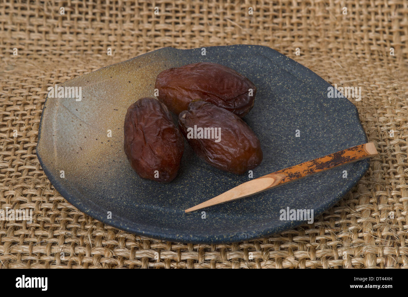 Dates on a ceramic plate and bamboo stick Stock Photo