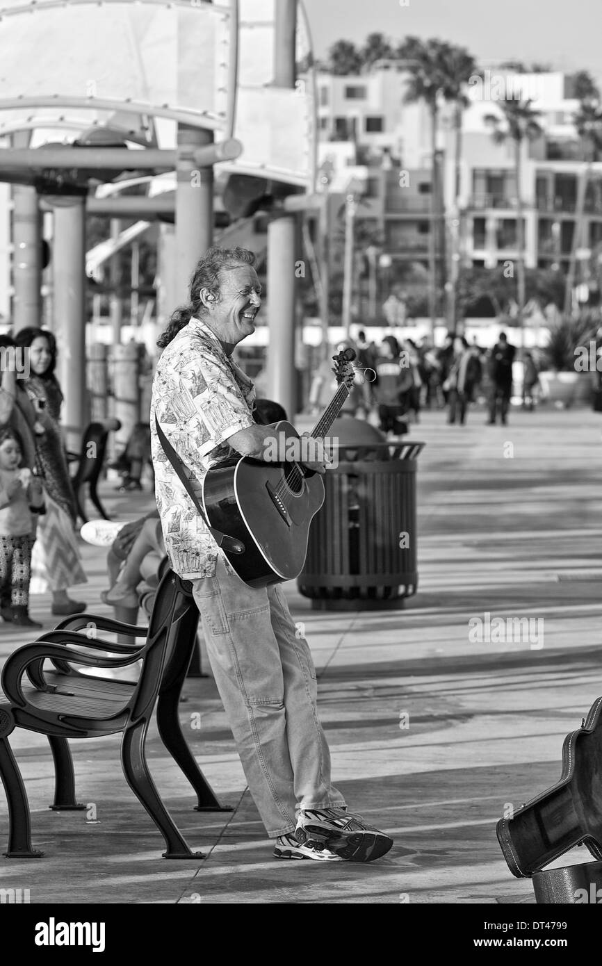 Black And White Photo Of A Street Performer (Busker) Playing The Guitar On Redondo Pier, Los Angeles, California, USA Stock Photo