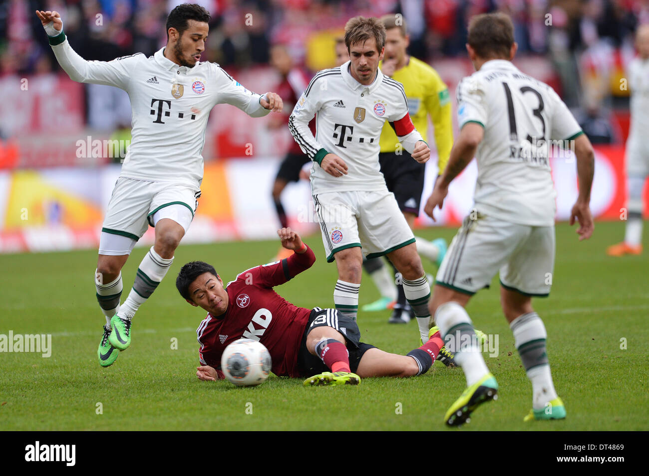 Nuremberg, Germany. 08th Feb, 2014. Nuremberg's Hiroshi Kiyotake (ON THE GROUND) vies for the ball with Munich's Thiago Alcantara (L-R), Philipp Lahm and Rafinha during the Bundesliga soccer match between 1. FC Nuremberg and FC Bayern München at Grundig-Stadium in Nuremberg, Germany, 08 February 2014. Photo: DAVID EBENER/DPA (ATTENTION: Due to the accreditation guidelines, the DFL only permits the publication and utilisation of up to 15 pictures per match on the internet and in online media during the match.)/dpa/Alamy Live News Stock Photo