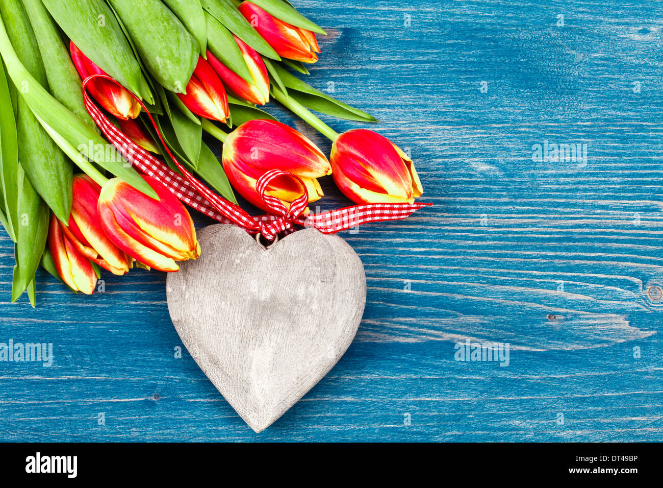 Tulip bouquet on blue background and wooden heart Stock Photo