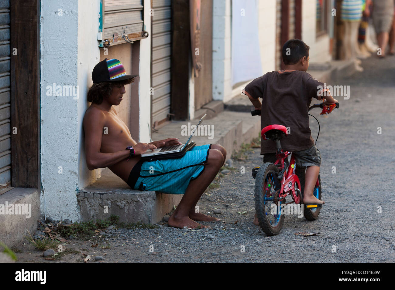 A surf instructor uses technology on the street with wifi in El Tunco, a beach town in El Salvador popular with surfers. Stock Photo