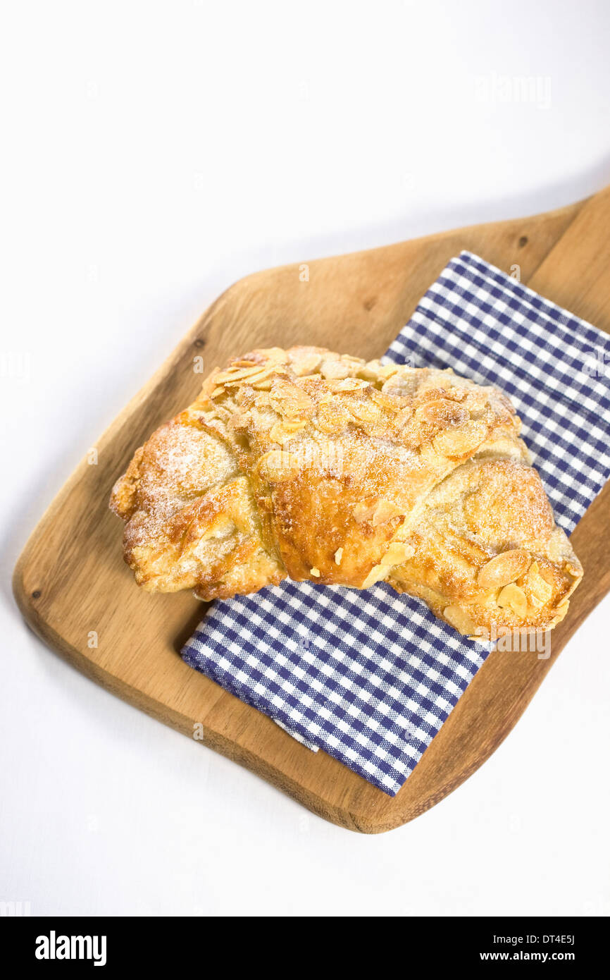 Almond croissant. Single crescent shaped french pastry on a wooden board. Stock Photo