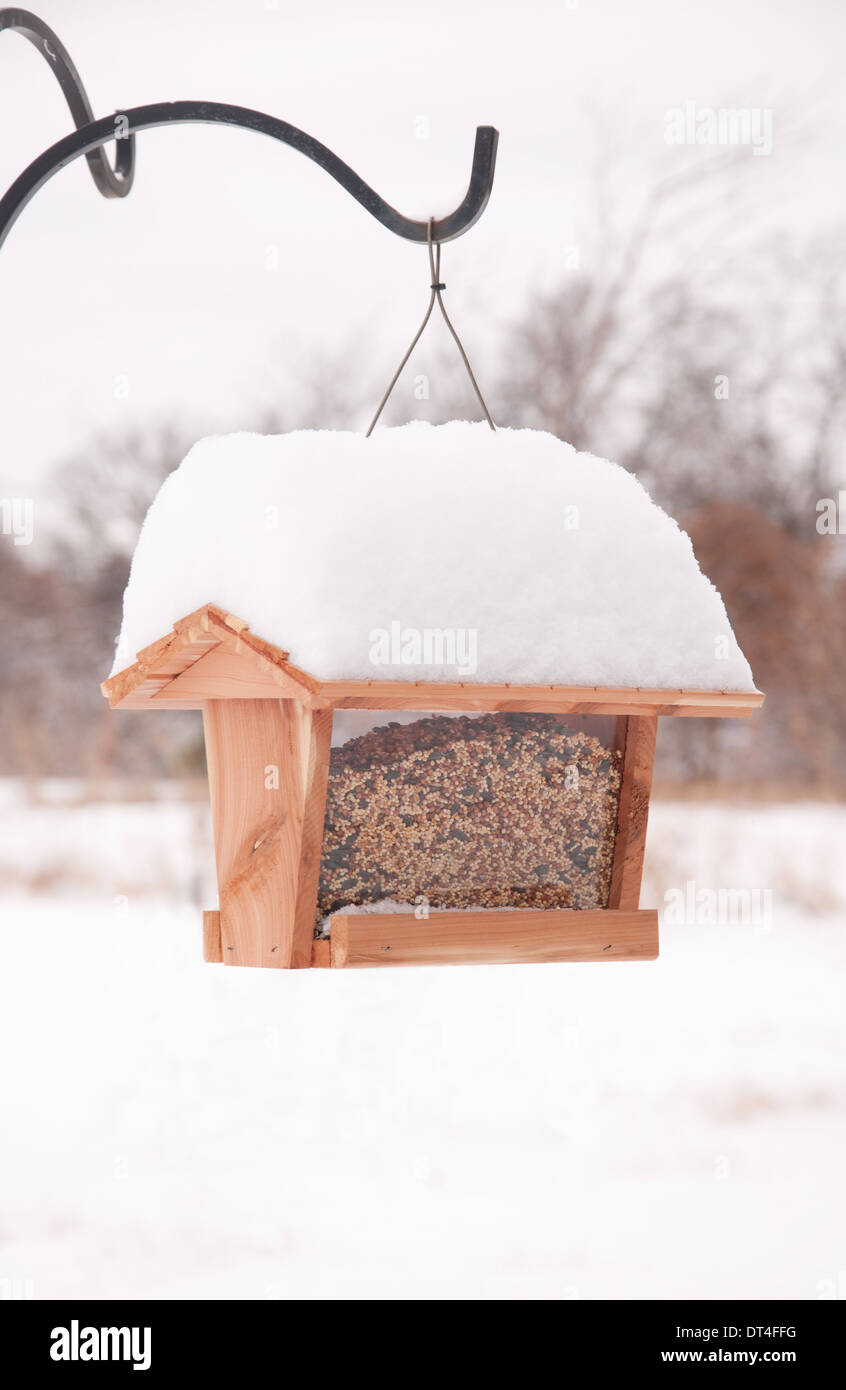 Bird feeder filled up with seeds, covered in heavy snow in winter Stock Photo