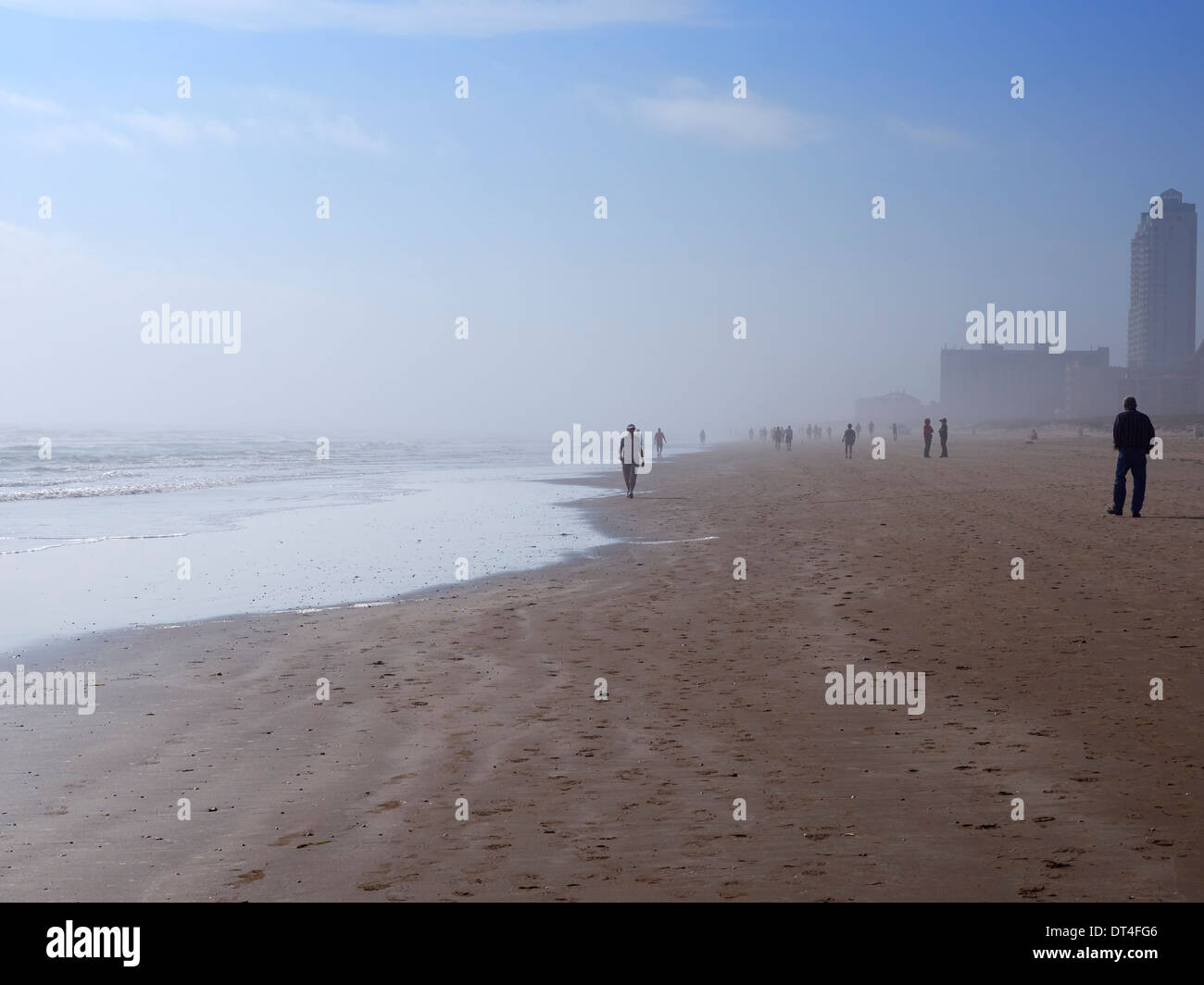 Tourists walk on the beach on a foggy morning in winter in South Padre Island, Texas Stock Photo