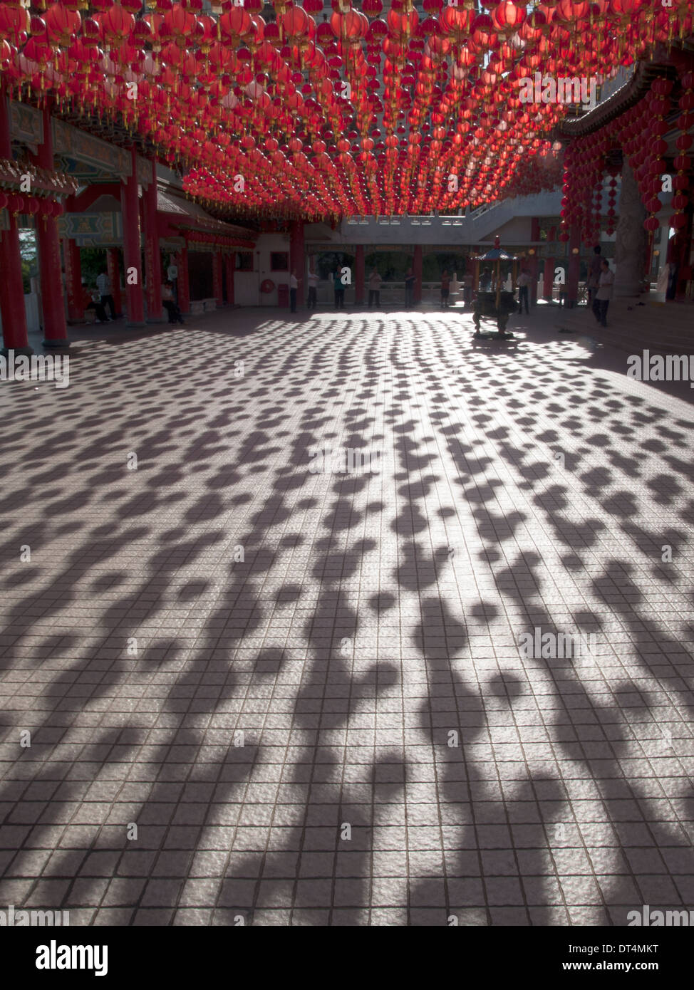 multitudes of auspicious red lanterns form a canopy, casting its patterned shadow over a Malay Chinese temple courtyard. Stock Photo