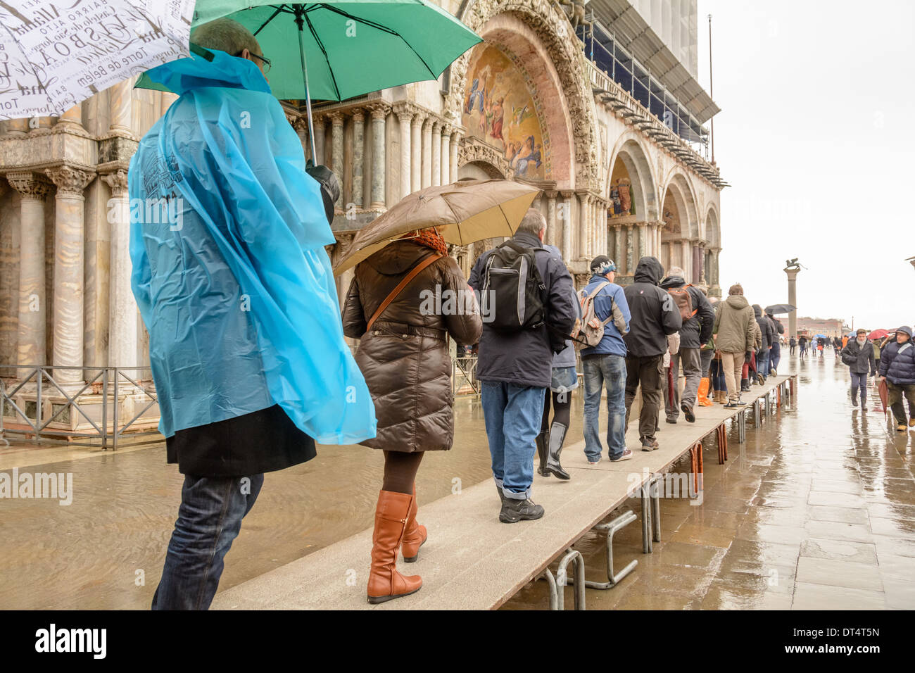 Venice, Italy. Tourists on acqua alta (high water) gangways queuing to enter the San Marco Basilica. Stock Photo