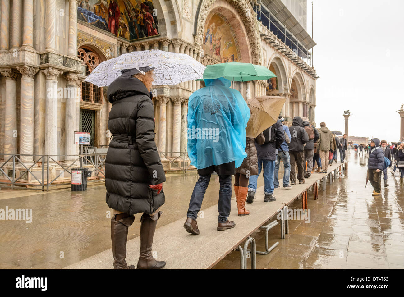 Venice, Italy. Tourists on acqua alta (high water) gangways queuing to enter the San Marco Basilica. Stock Photo