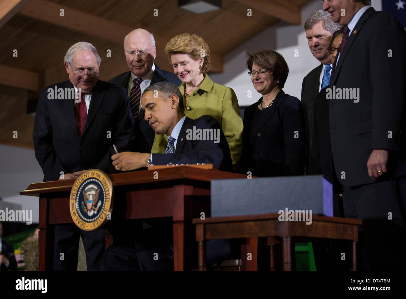 US President Barack Obama signs the Agricultural Act of 2014 known as the Farm Bill during a ceremony at Michigan State University February 7, 2014 in East Lansingg, MI. Standing with the president are (L-R) Senators Carl Levin, Patrick Leahy, Debbie Stabenow, Amy Klobuchar and Agriculture Secretary Tom Vilsack. Stock Photo