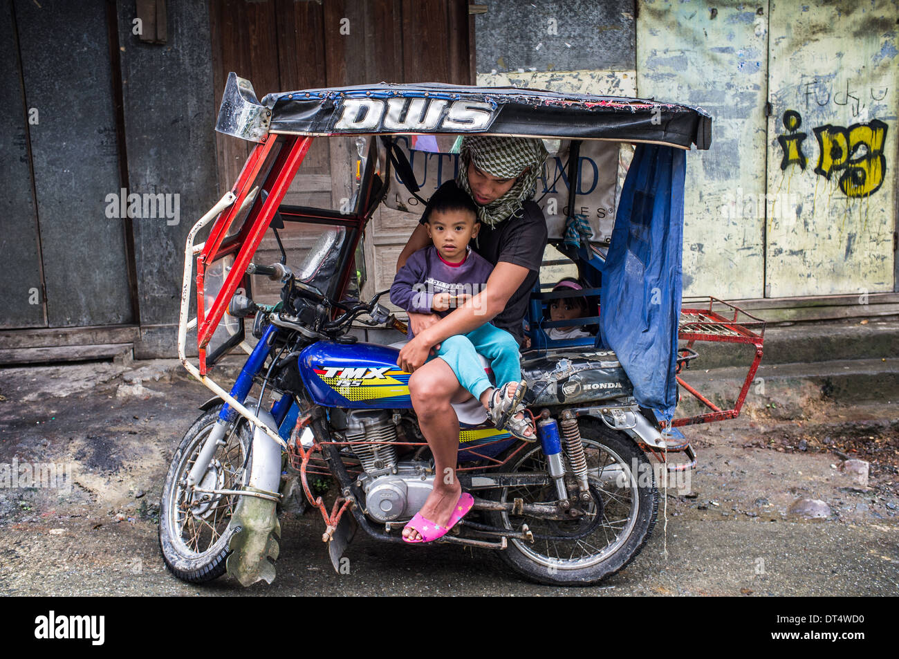 father with a child sitting on a tricycle, Philippines Stock Photo