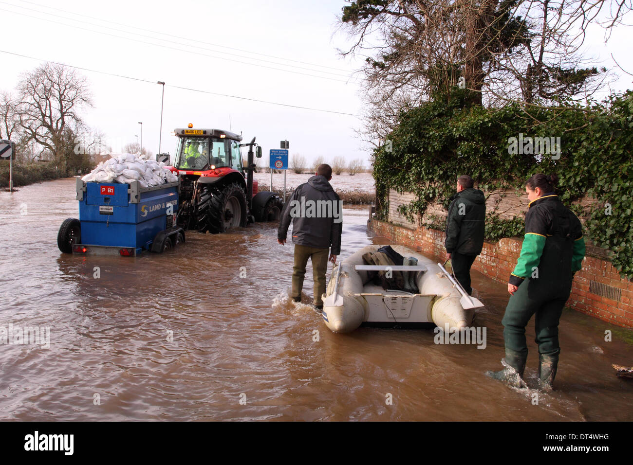 Burrowbridge, Somerset, UK. 9th Feb 2014. Tractor with a trailer full of sandbags drives through flood water on the A361 at Burrowbridge with volunteers following by boat. Stock Photo