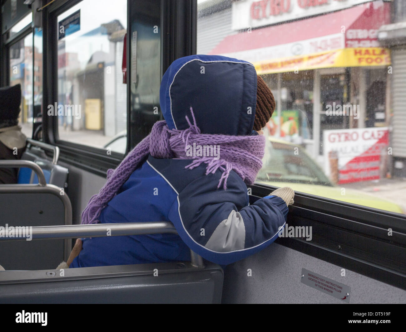 Child looks out a window on a public bus, Brooklyn, NY. Stock Photo