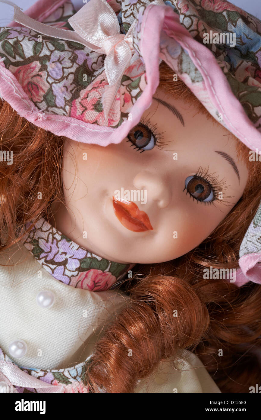 Close up of face of porcelain doll with ringlets wearing a hat Stock Photo