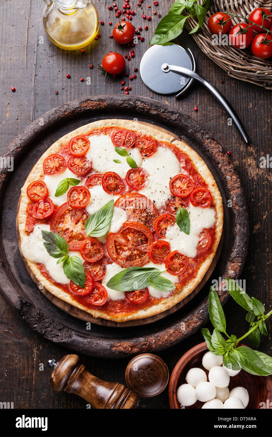 Italian pizza with tomatoes and mozzarella on wooden table Stock Photo