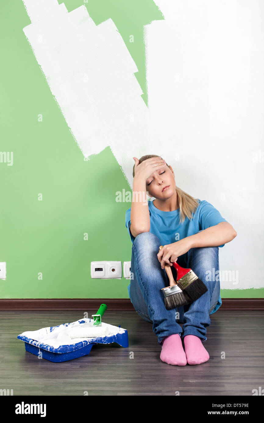 Tired woman with paint tools in hand Stock Photo