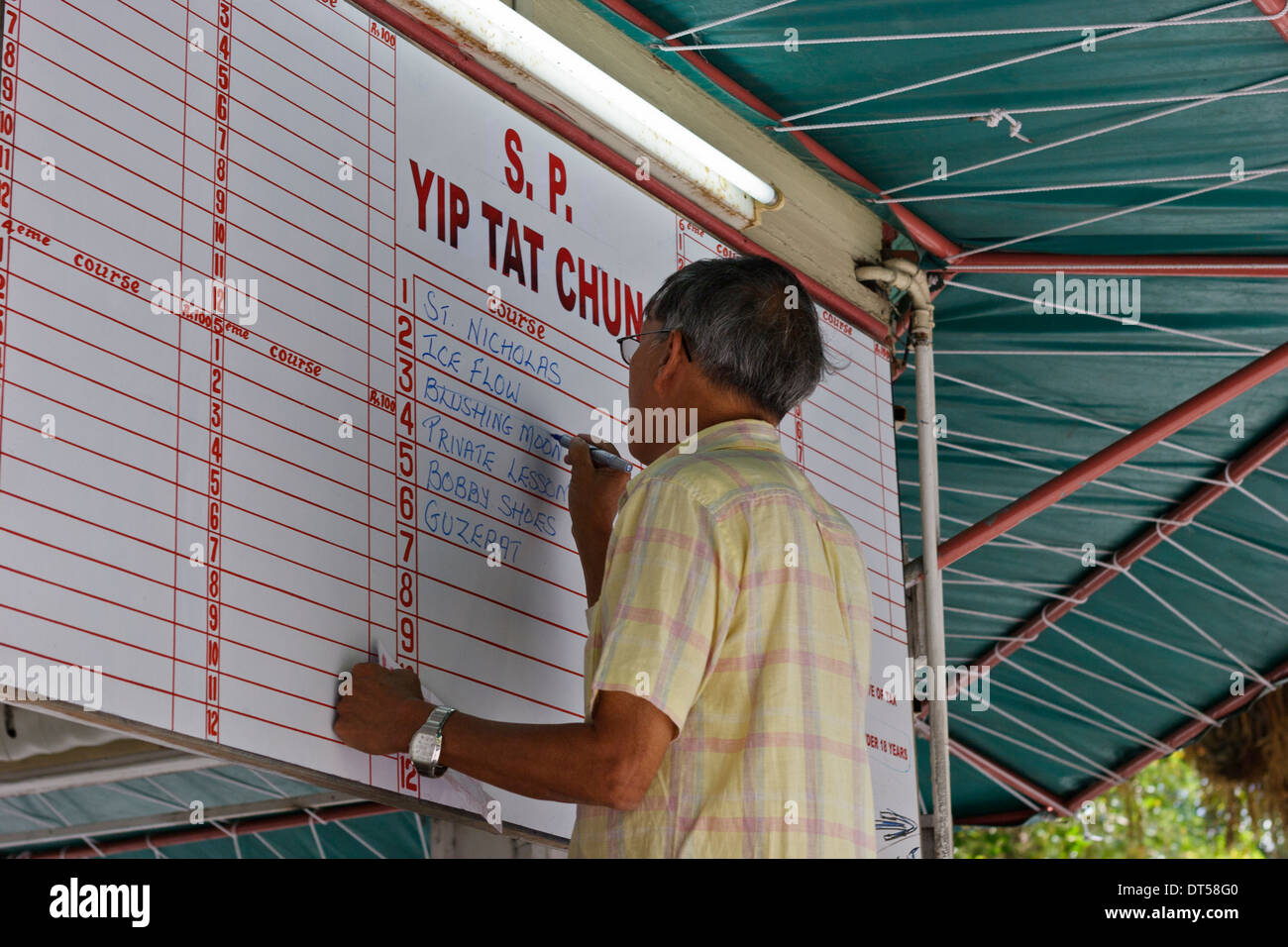 A bookmaker updating the betting board, Champs de Mars, Mauritius. Stock Photo