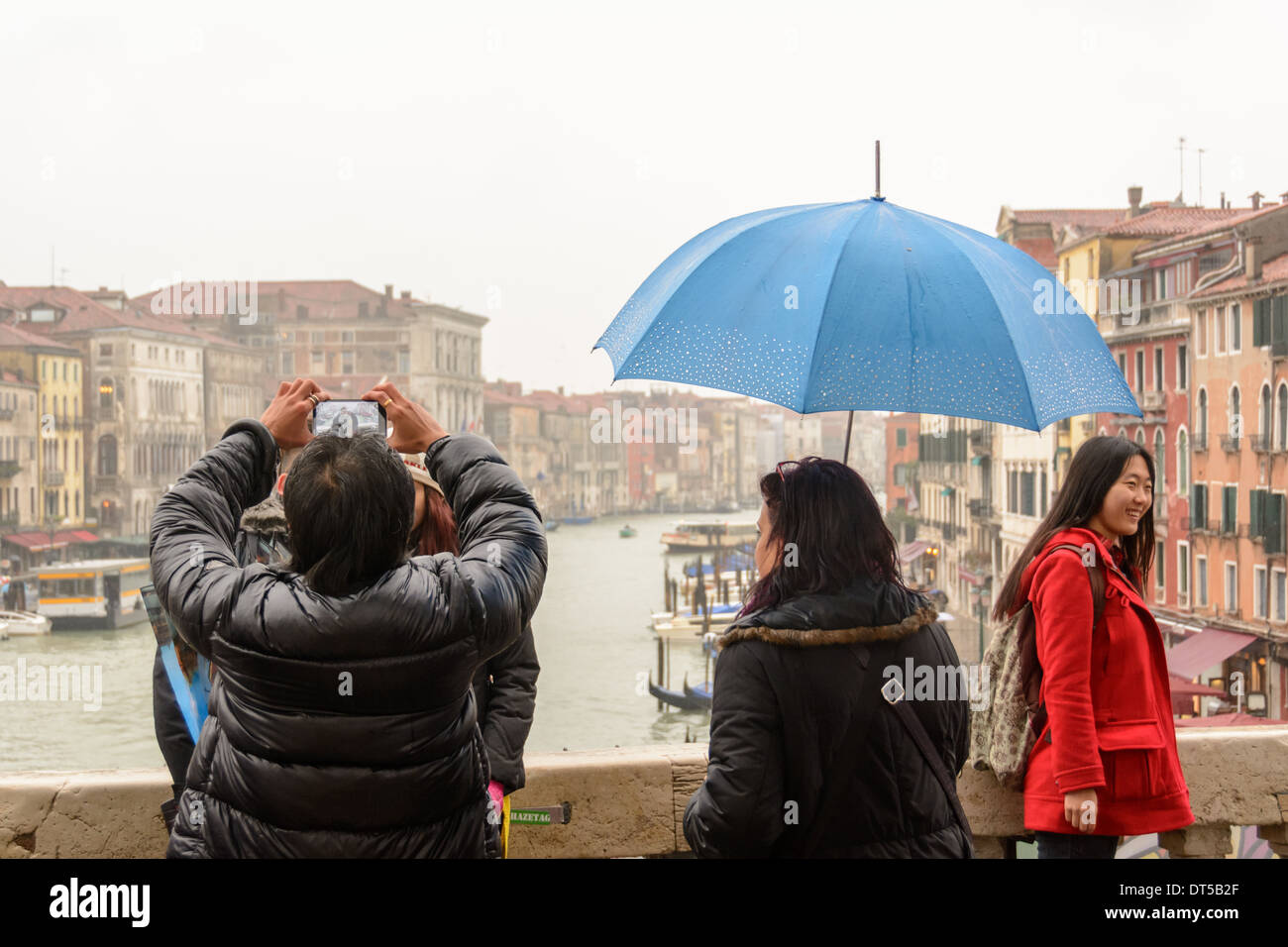 Venice, Italy. View over the Grand Canal through the display of a smartphone from a man taking pictures from an Asian couple. Stock Photo