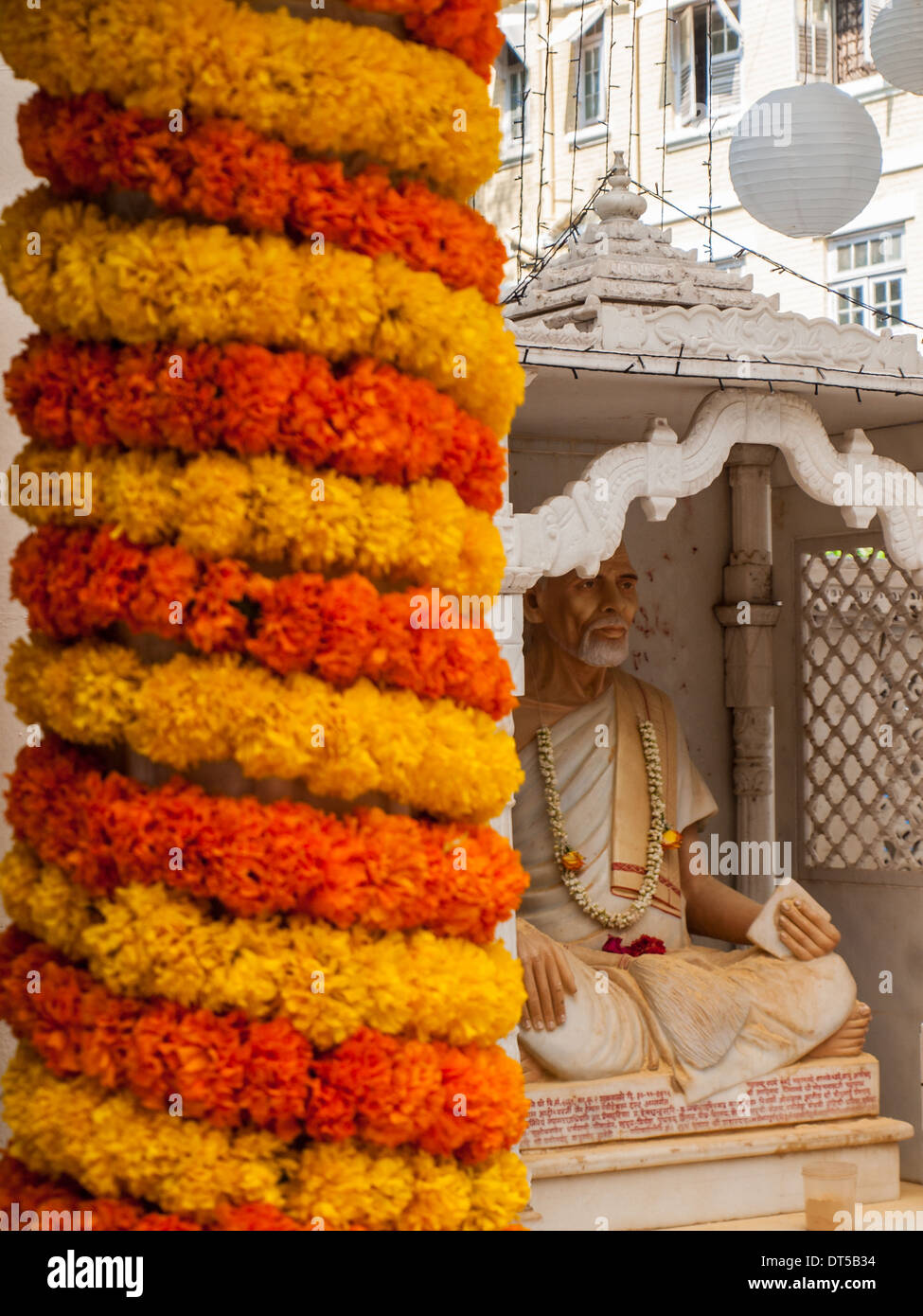 Flower arrangement with statue in background in Babu Amichand Panalal Adishwarji Jain temple Stock Photo