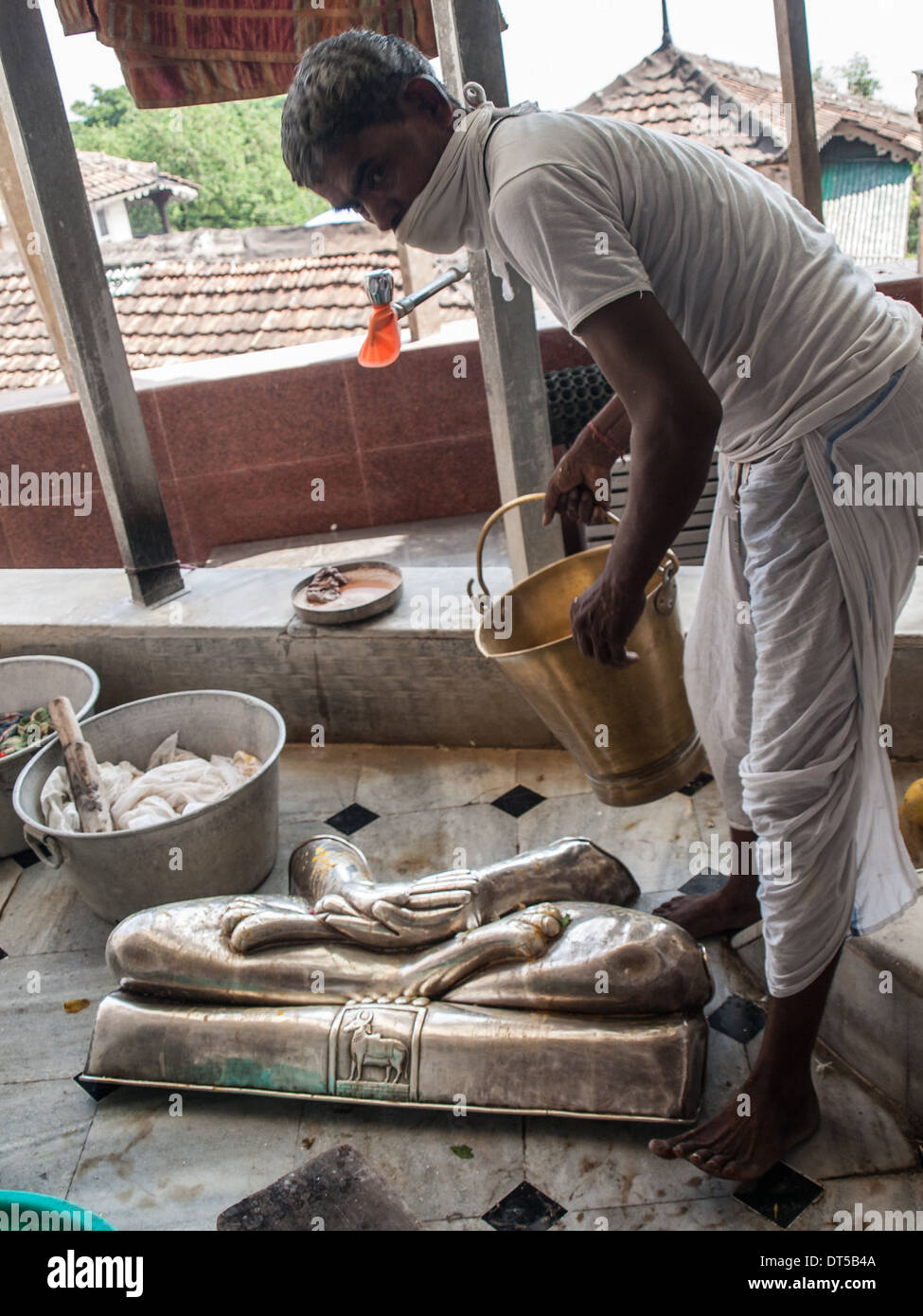 Man cleaning Jain Gods silver statues parts in Babu Amichand Panalal Adishwarji temple Stock Photo