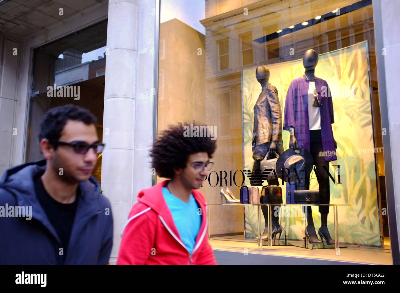 Two young affluent ethnic men walking past Emporio Armani designer fashion boutique on Bond street, London Stock Photo